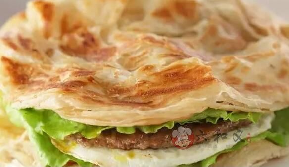 摩登7快餐/></a></p>
<p>材料:</p>
<p>面粉、盐、食用油、水、火腿、酱料、蔬菜</p>
<p>1、准备2份面粉一份用开水和开搅拌一份用凉水和适量的盐搅拌,拌成雪花状,分别揉成光滑面团</p>
<p>2、将2个面团用保鲜膜包好放置半个小时</p>
<p>3、案板上抹油,把两个面团压扁,用手一个方向搓成条</p>
<p>4、电饼铛提前预热好,刷上一层食用油,放入擀好的饼,在面皮上撒一层薄薄的腌过的葱花,均匀地撒满。等一面烙成金黄色时,反面,烙</p>
<p>另一面。</p>
<p>5、把一份饼煎成两面都呈金黄色。用筷子把煎好的饼从中间挑松即可。</p>
<p>6、可以在饼铛上烙上几片火腿,一个鸡蛋,等鸡蛋快要凝固的时候,把饼盖在鸡蛋上,等鸡蛋完全凝固后,取出,刷上自己喜欢的酱料,放上火腿、蔬菜,卷起来,吃吧!</p>
<p style= 摩登7快餐配送